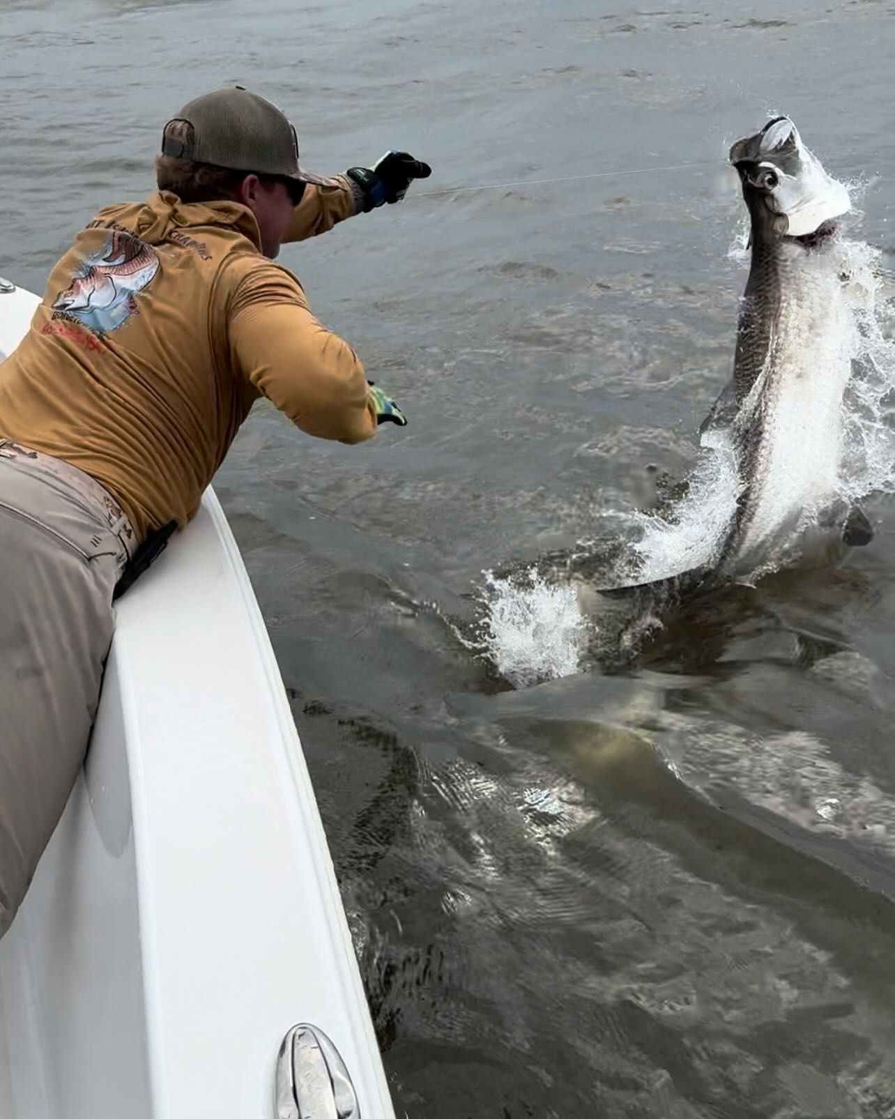 A man on a boat is catching a fish in the water.