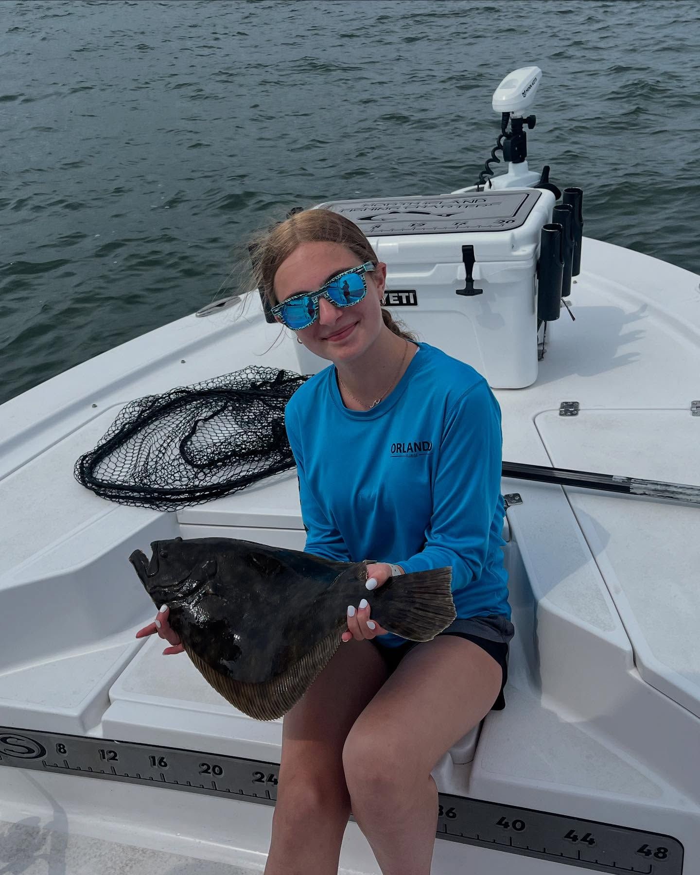 A woman is sitting on a boat holding a fish