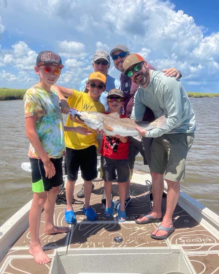A group of people are standing on a boat holding fish.