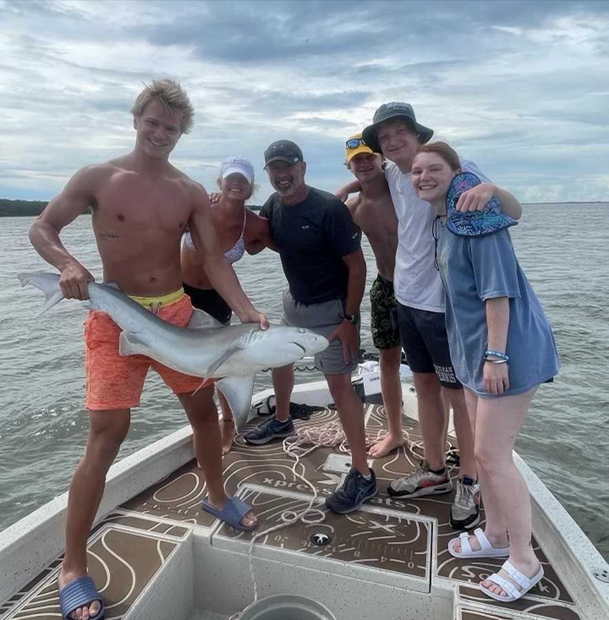 A group of people standing on a boat holding a shark