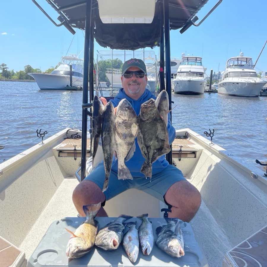 A man is sitting on a boat holding two fish