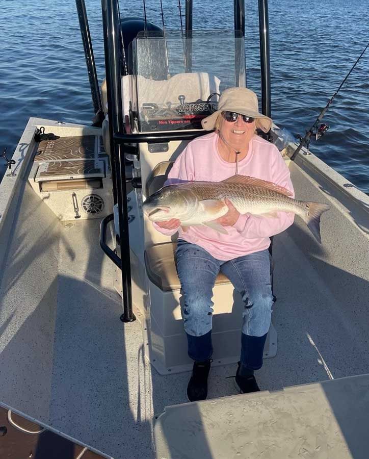 A woman is sitting on a boat holding a large fish.