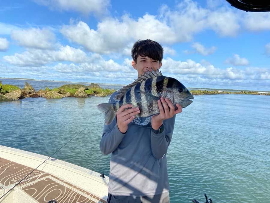 A young boy is holding a fish in his hands on a boat.