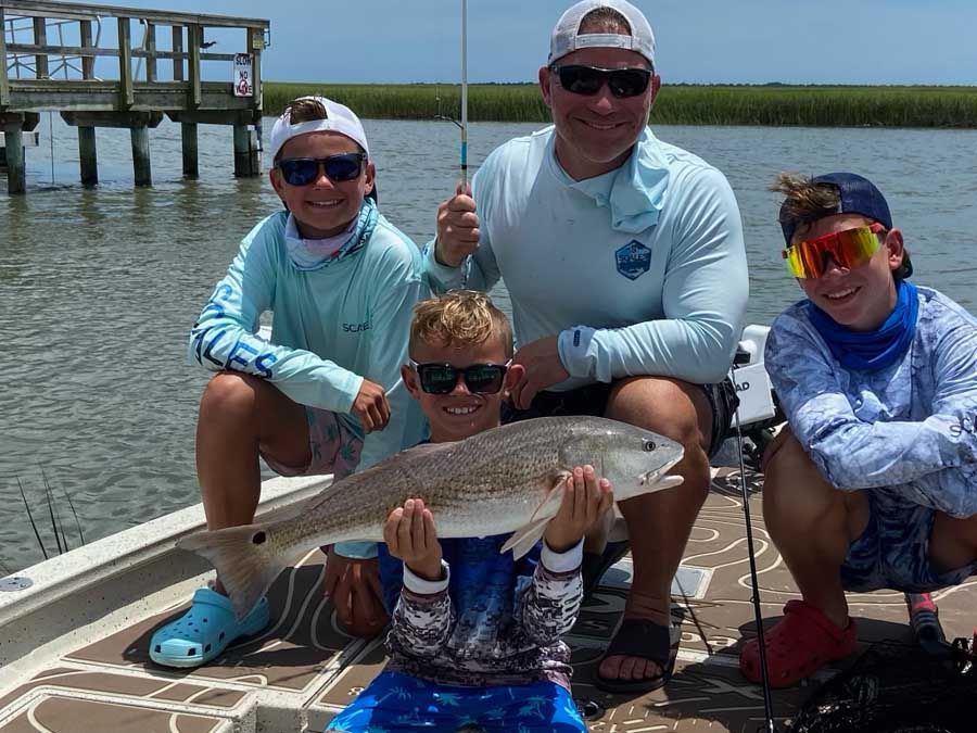 A group of people are sitting on a boat holding a fish.