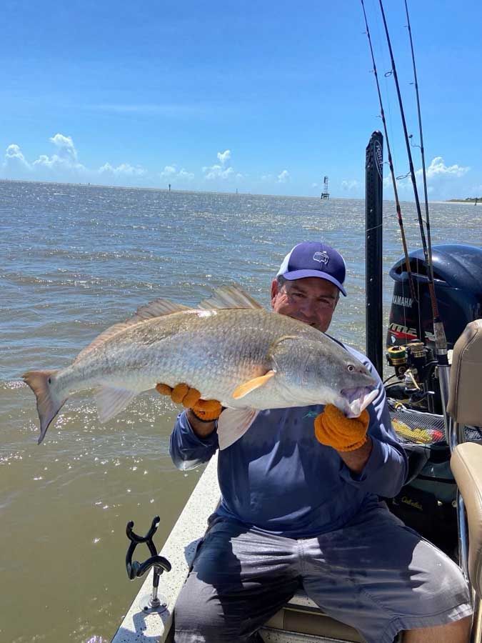 A man is sitting on a boat holding a large fish.
