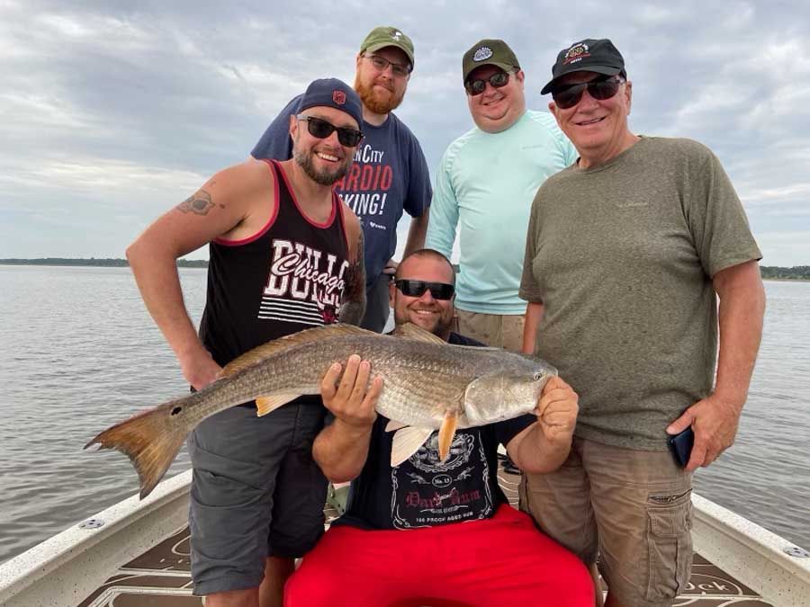 A group of men are standing on a boat holding a large fish.