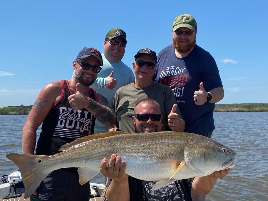 A group of men are posing for a picture while holding a large fish.