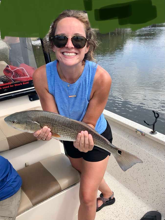 A woman is holding a large fish on a boat.