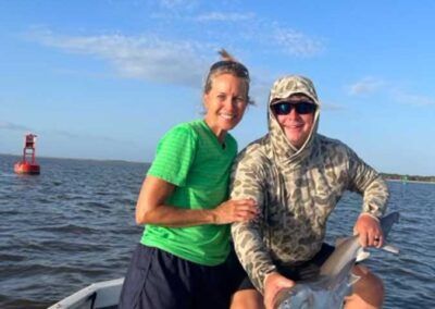 A man and a woman are sitting in a boat holding a fish.