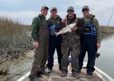 A group of men are standing on a boat holding a fish.