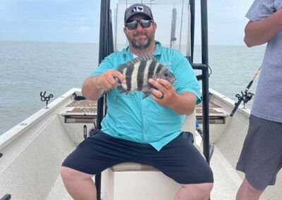 A man is sitting on a boat holding a fish.