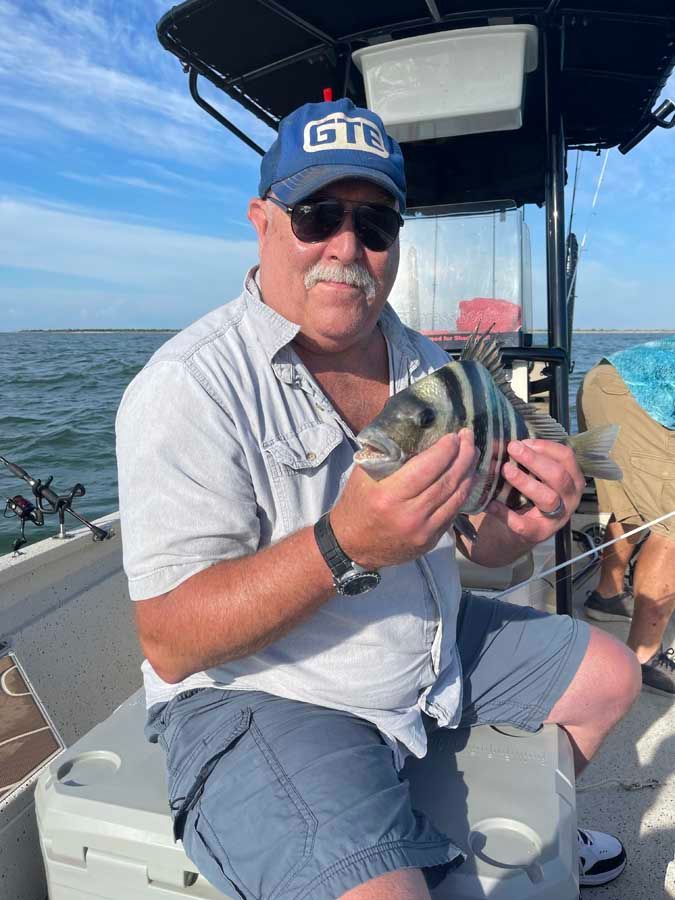 A man is sitting on a boat holding a fish.