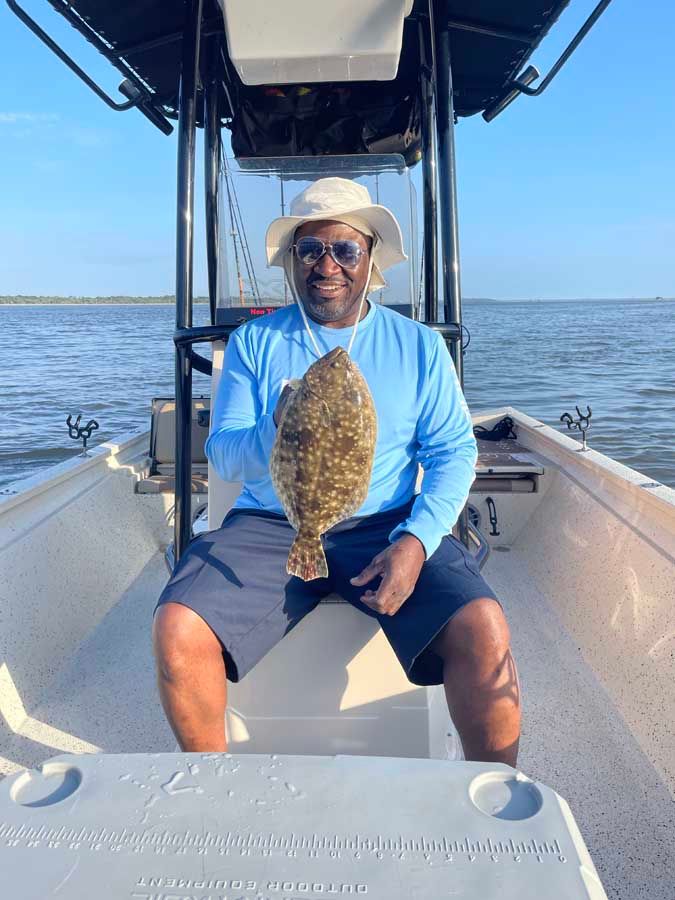A man is sitting on a boat holding a fish.