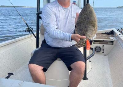 A man is sitting on a boat holding a fish.