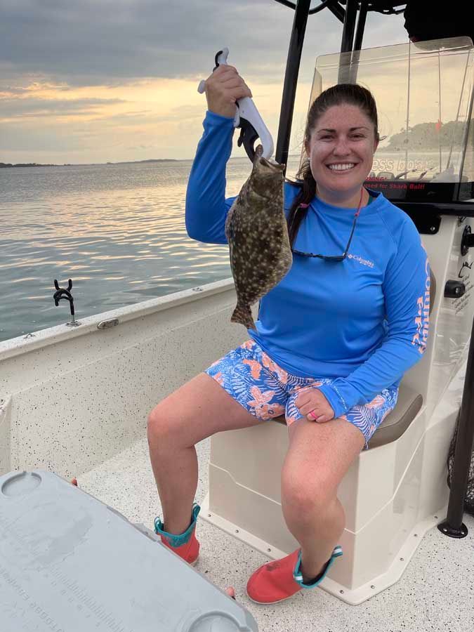 A woman is sitting on a boat holding a fish.