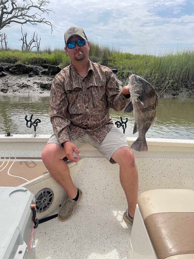 A man is sitting on a boat holding a large fish.