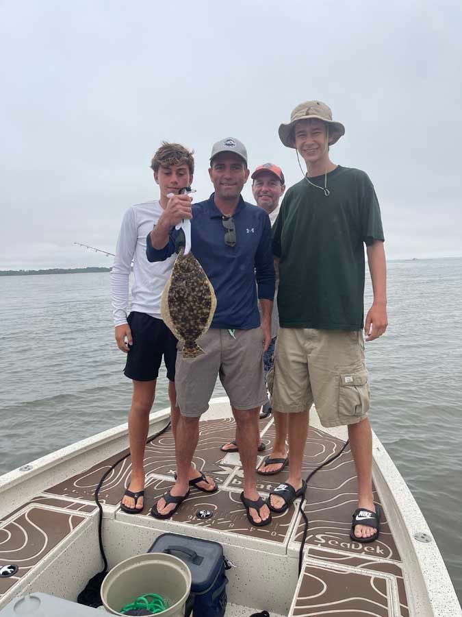 A group of men are standing on a boat holding a fish.