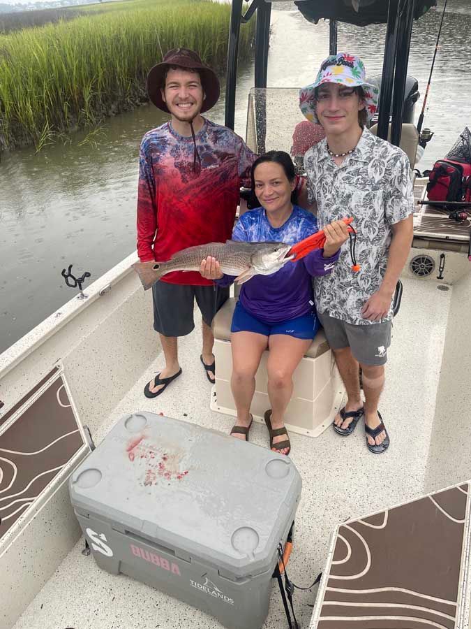 A group of people are standing on a boat holding a fish.