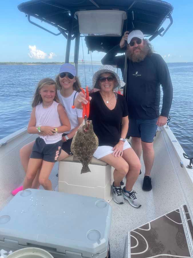 A family is sitting on a boat holding a fish.