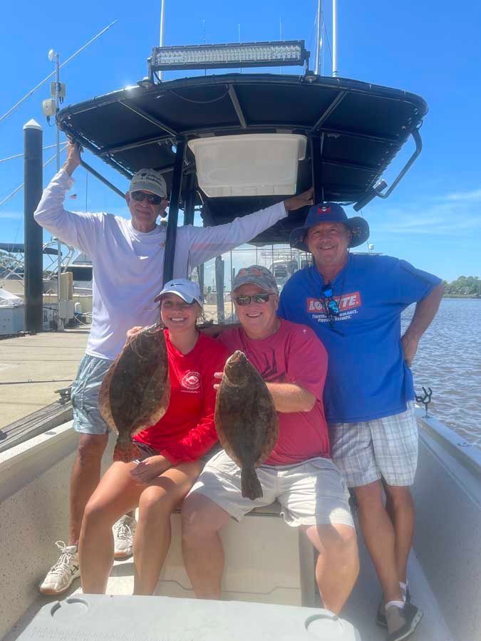 A group of people are standing on a boat holding fish.