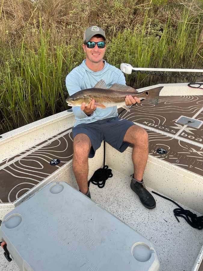 A man is sitting on a boat holding a fish.