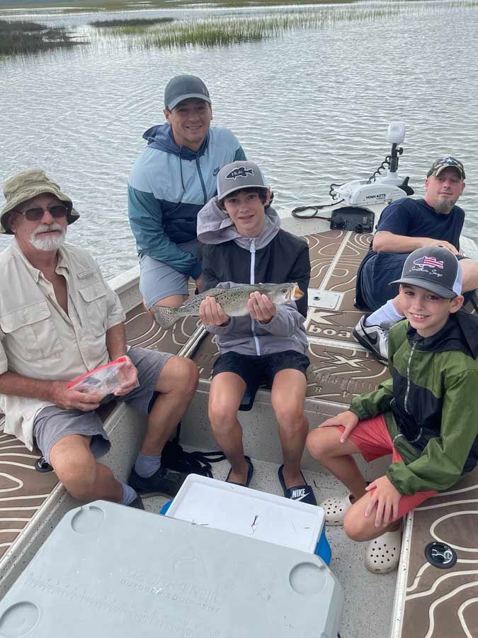 A group of people are sitting on a boat holding a fish.