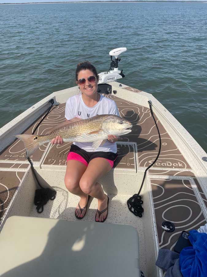 A woman is sitting on a boat holding a large fish.