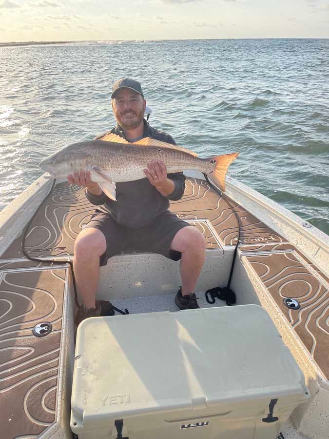 A man is sitting on a boat holding a large fish.