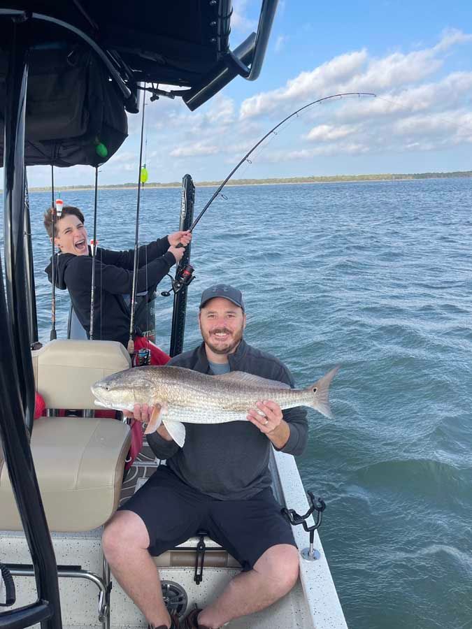 A man is sitting on a boat holding a large fish.