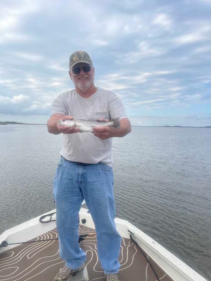 A man is standing on a boat holding a fish in his hands.