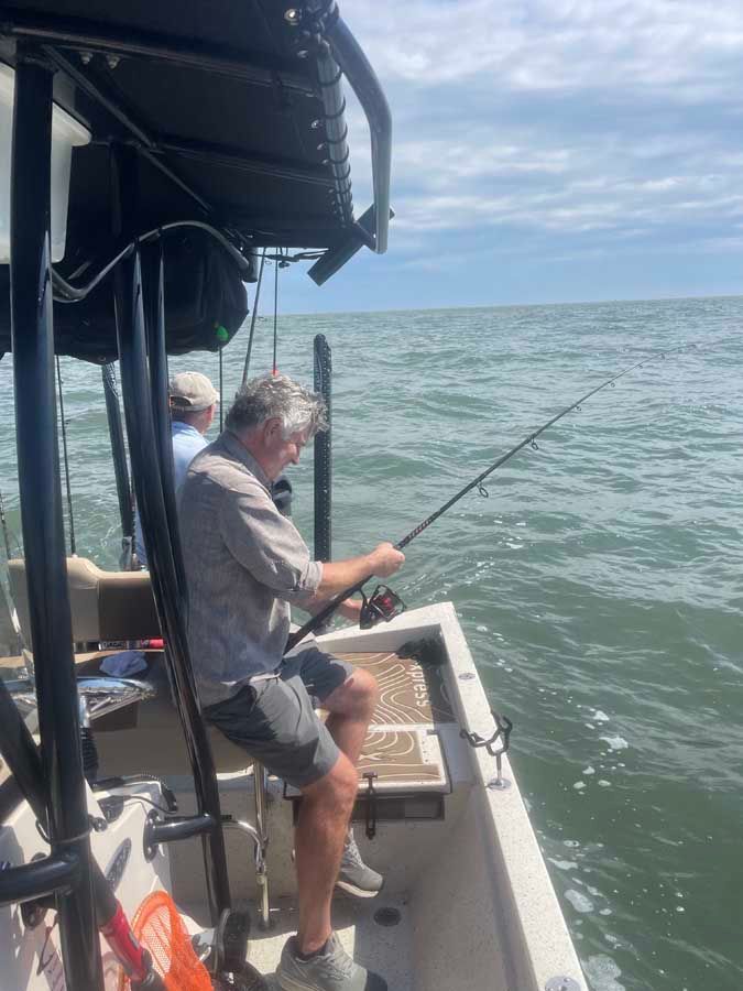 A man is fishing on a boat in the ocean.