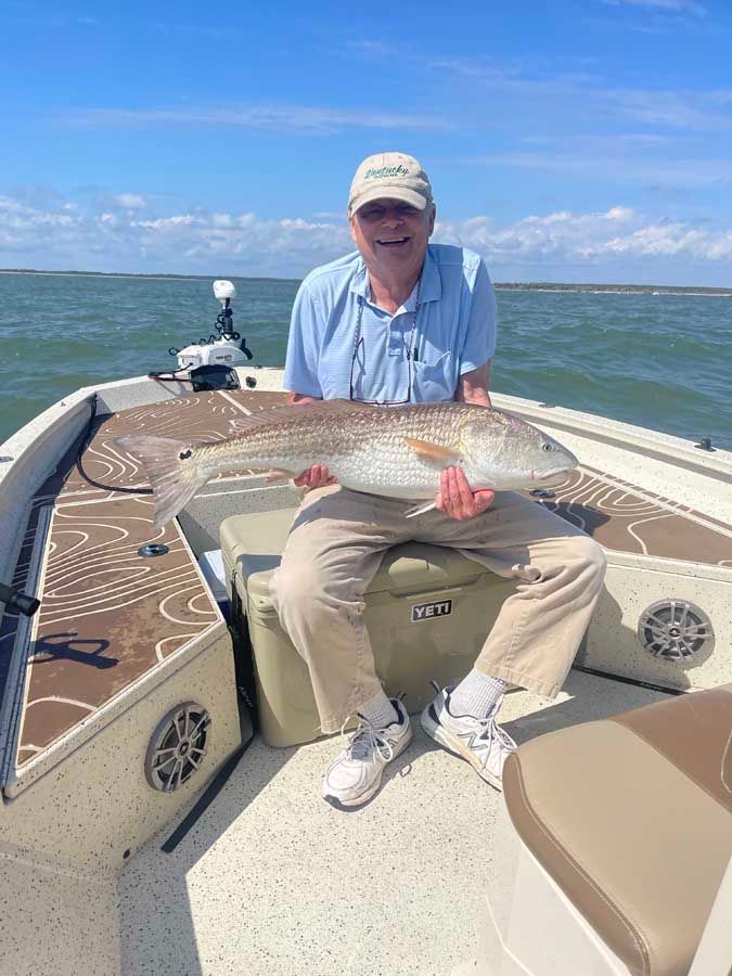 A man is sitting on a boat holding a large fish.