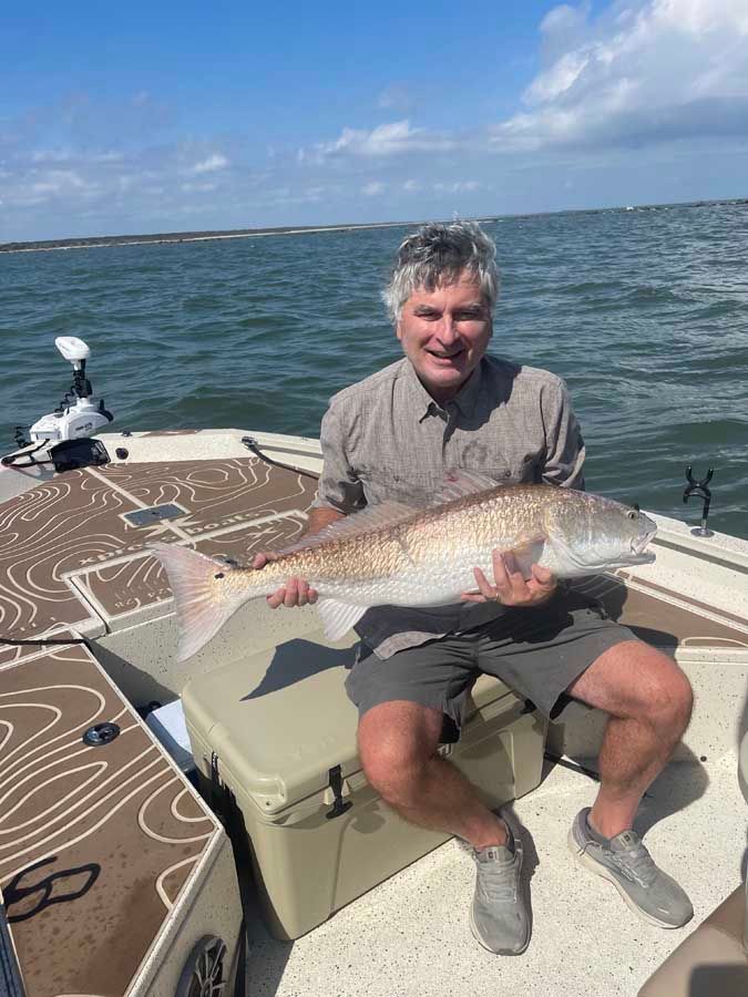 A man is sitting on a boat holding a large fish.