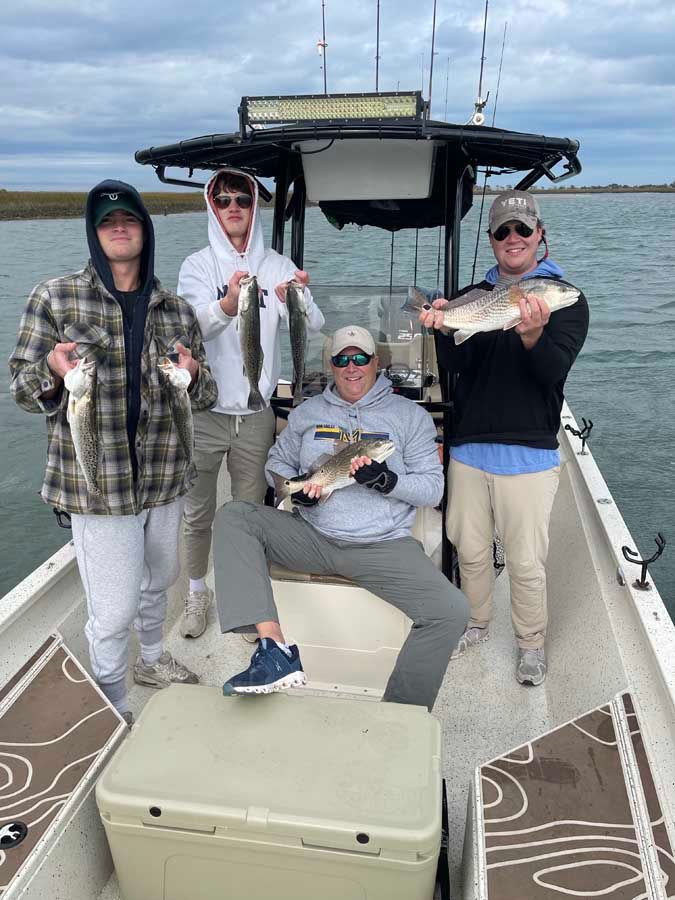 A group of men are standing on a boat holding fish.
