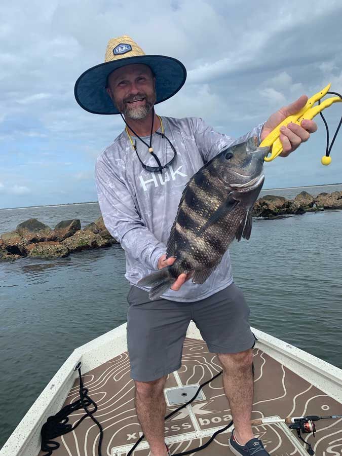 A man is standing on a boat holding a large fish.
