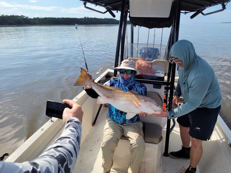 A man is holding a large fish on a boat.