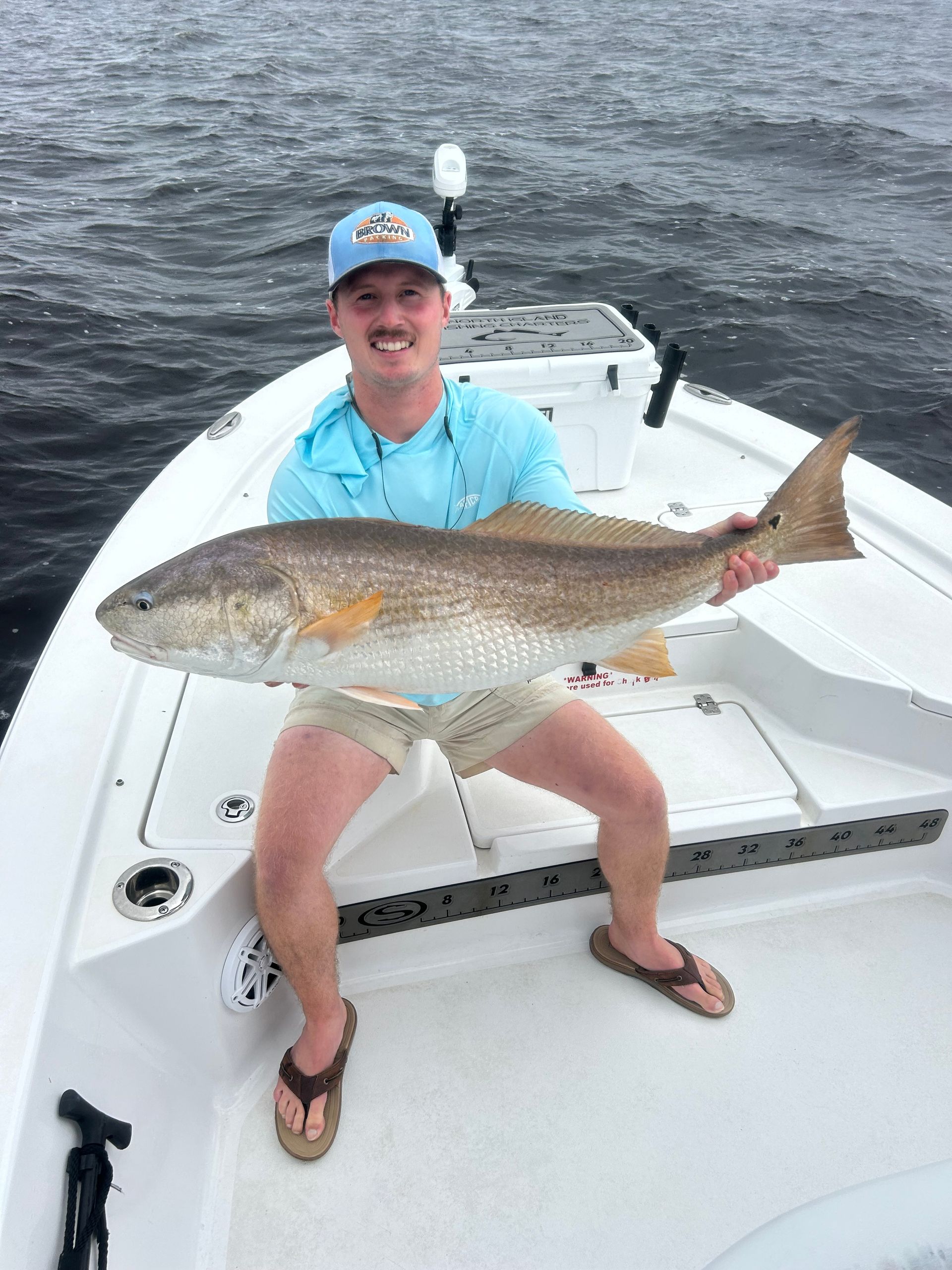 Two men are standing next to a boat with a bunch of ducks on it.