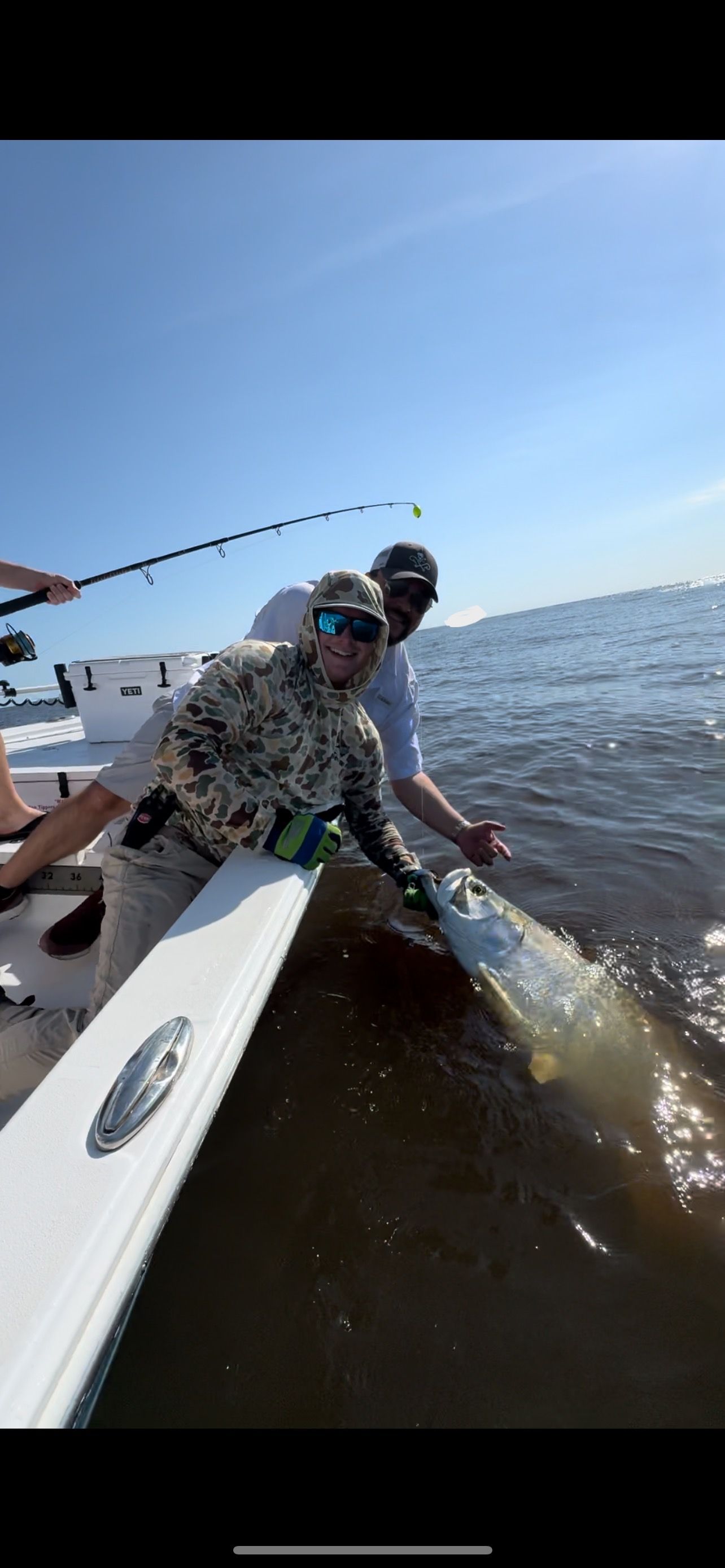 A man is sitting on a boat holding a large fish.