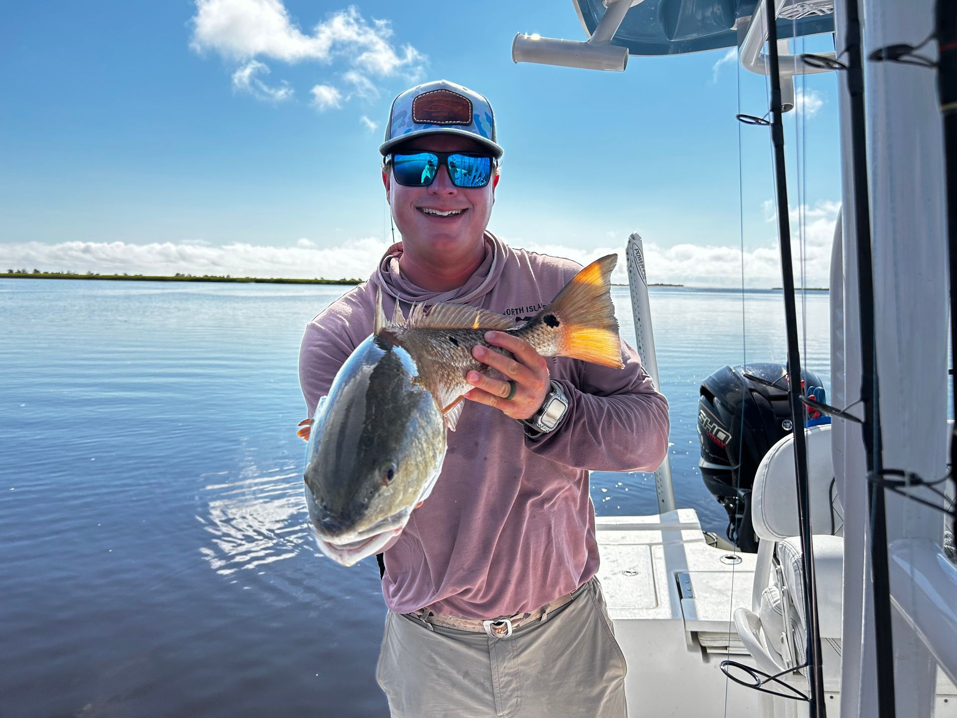 A man is sitting on a boat holding a large fish.