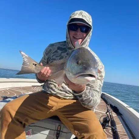 A man is sitting on a boat holding a large fish.