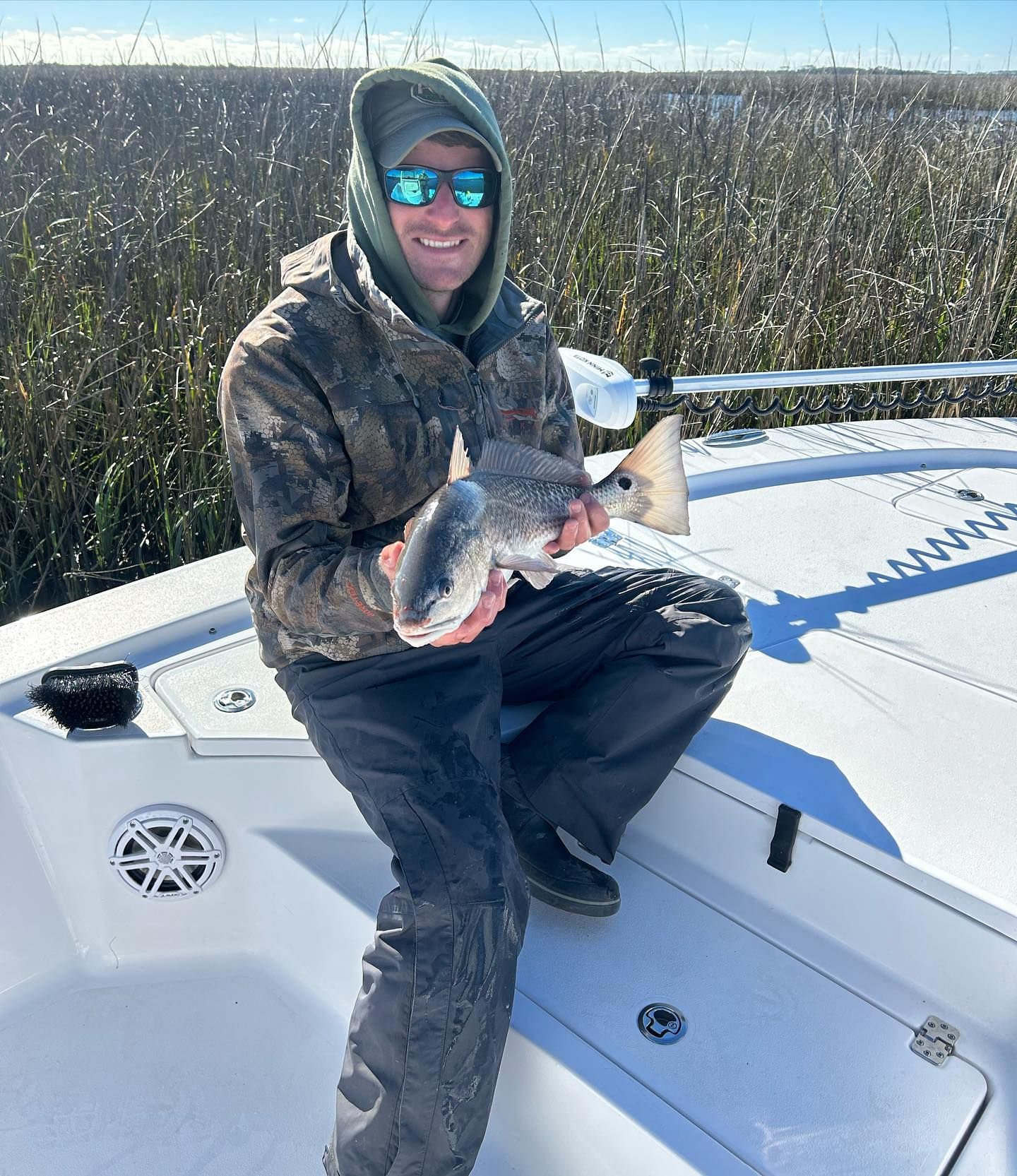 A man is sitting on a boat holding a fish.