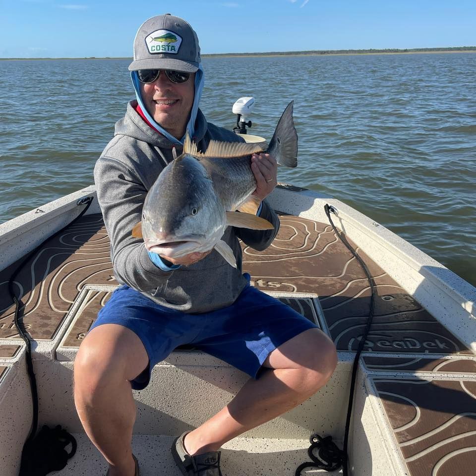 A man is sitting on a boat holding a large fish