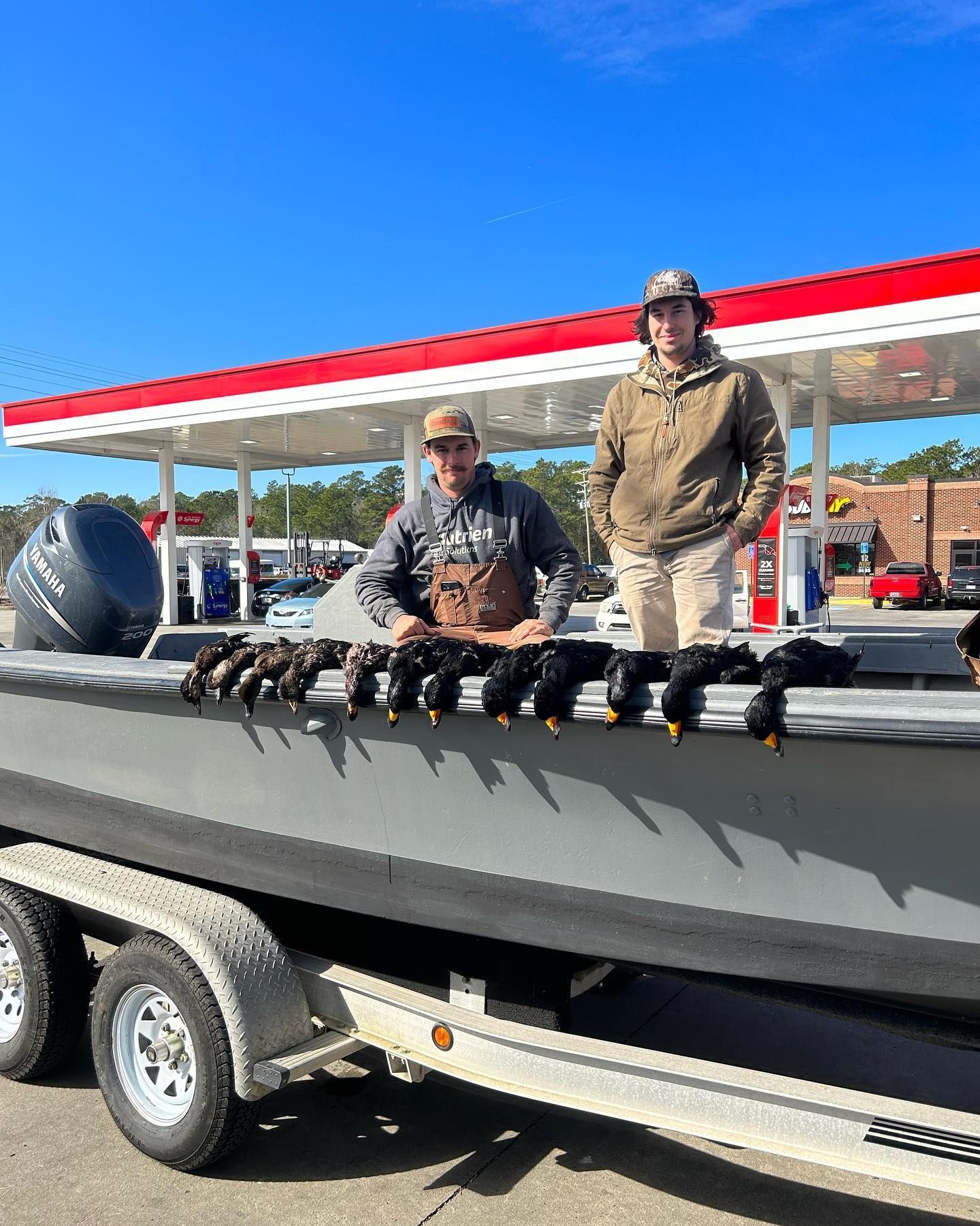 Two men are standing next to a boat with a bunch of ducks on it.