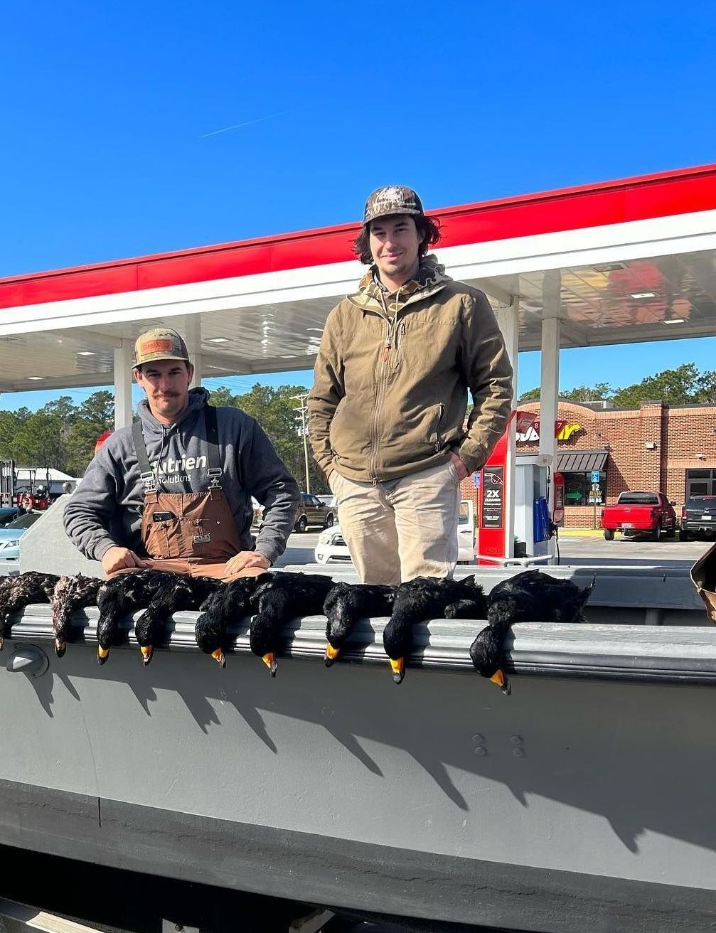 Two men in camo standing next to a boat