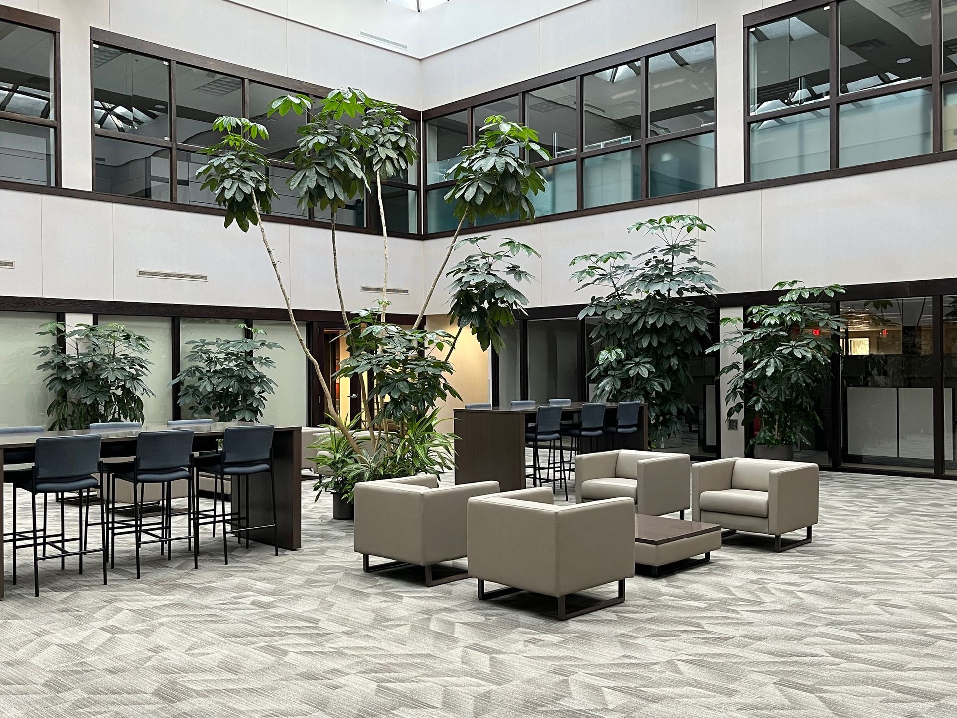 Indoor atrium with seating, greenery, and large windows.
