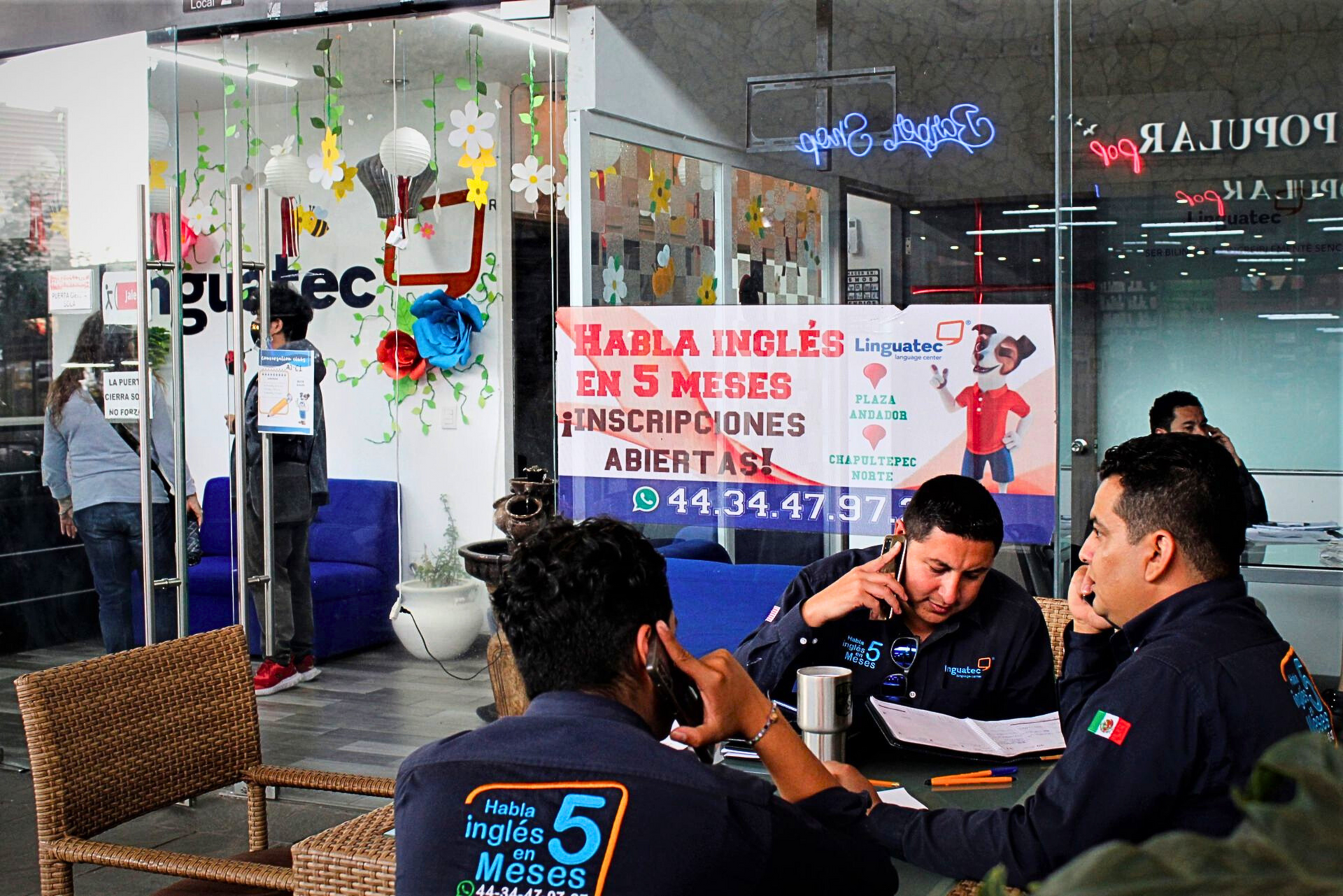Un grupo de hombres están sentados en una mesa frente a un cartel que dice tabla inglés