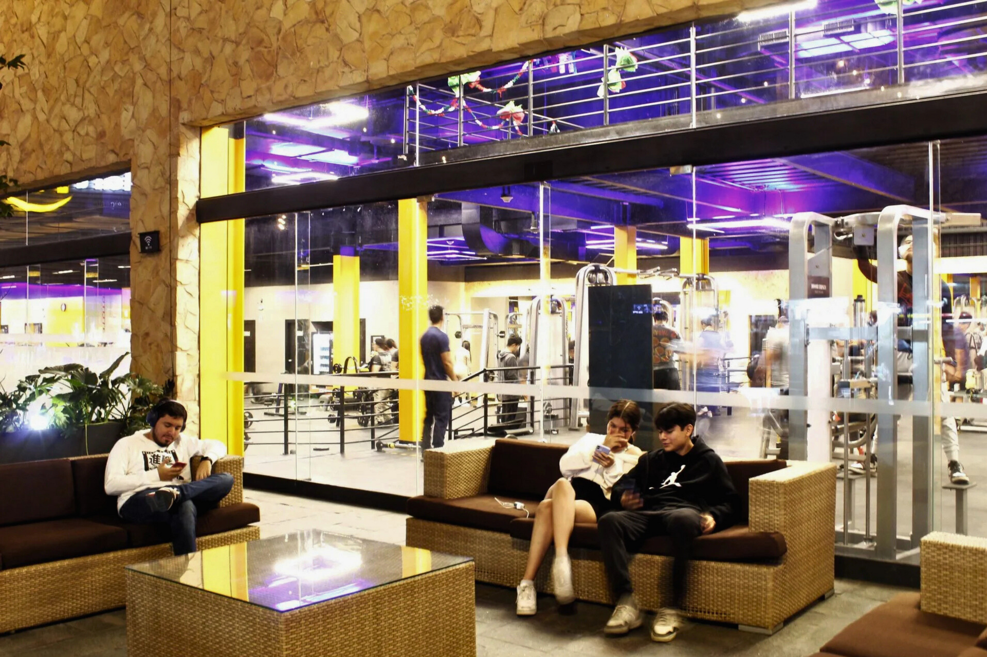 Un grupo de personas está sentada en un sofá en un gimnasio.