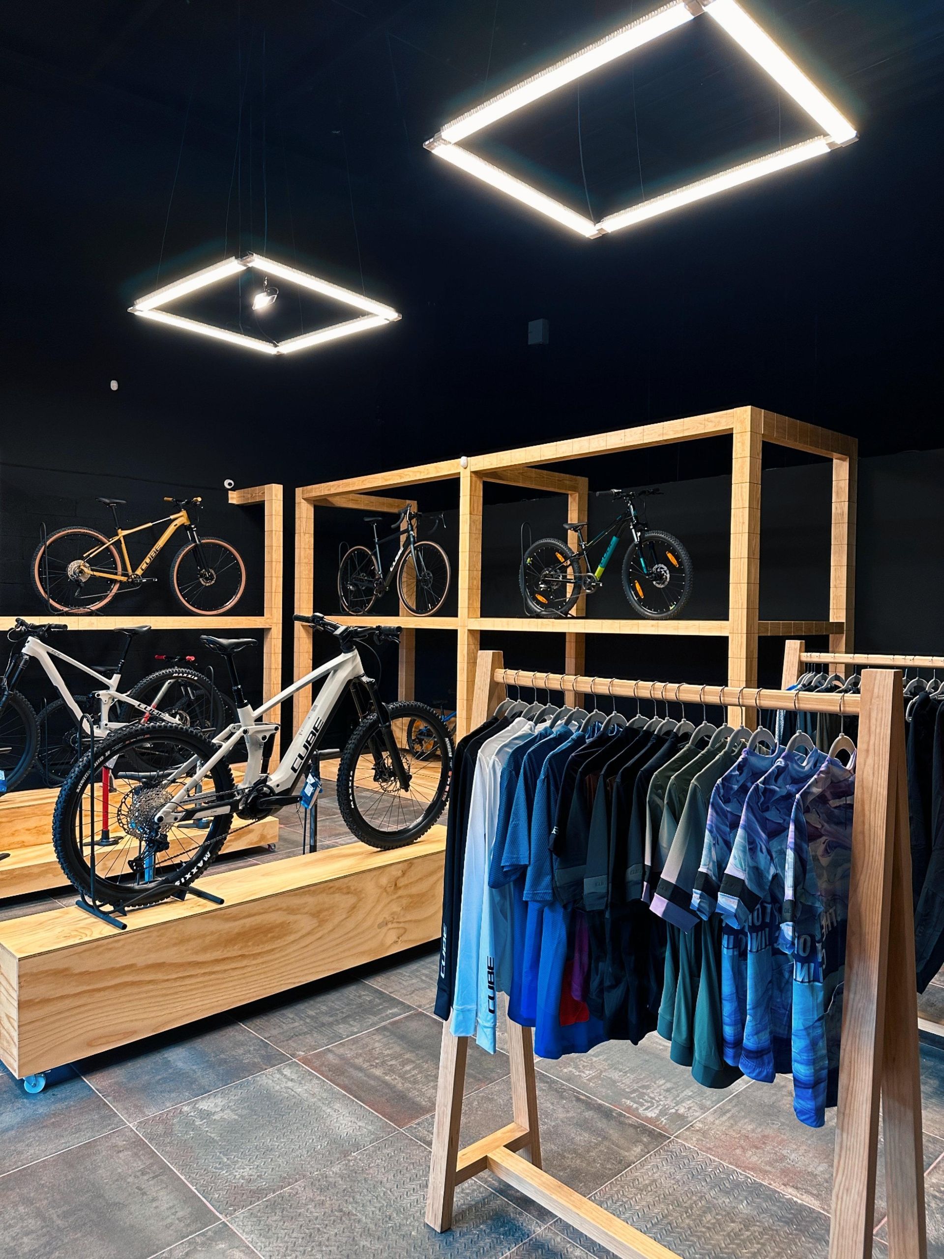 Una bicicleta se exhibe en una tienda junto a un estante de ropa.