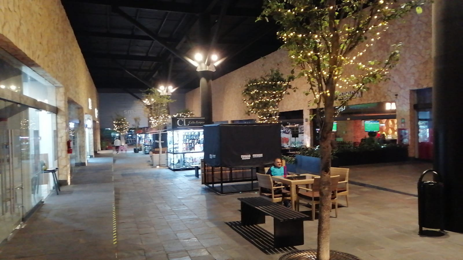 Un centro comercial con mesas y sillas y un árbol con luces