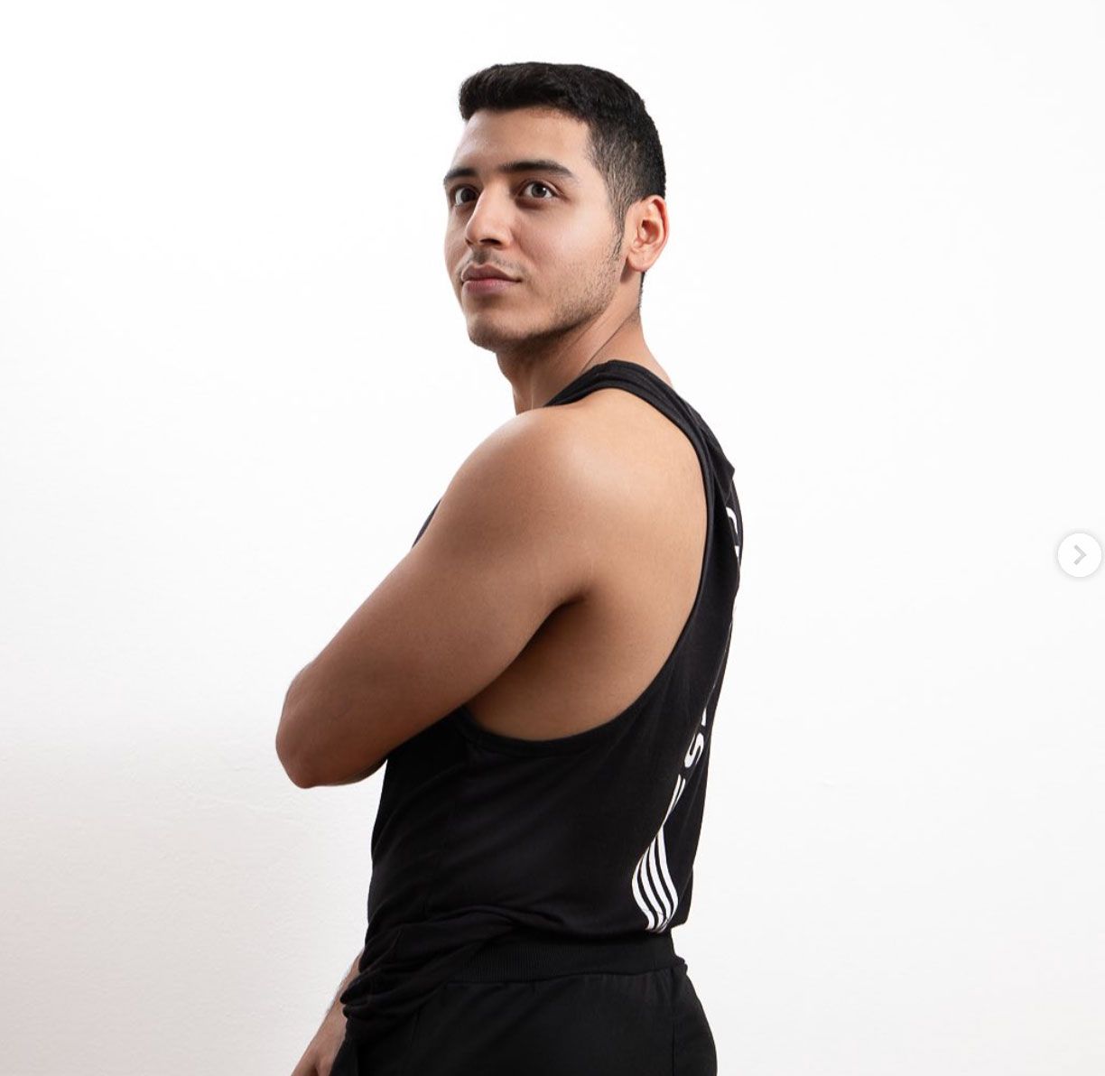 Un hombre con una camiseta negra está de pie con los brazos cruzados